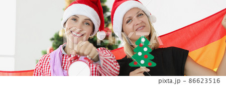 Two happy young women with lgbt flag holding New Year tree and happy alarm clock Two happy young women with lgbt flag holding New Year tree and happy alarm clock 86623516