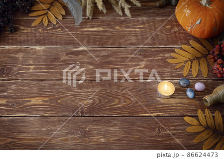 Autumn authentic layout on wooden backdrop with dry leaves, pumpkin, ashberry, agate gemstones, bottle, candle and feather, copy space, selective focus. 86624473