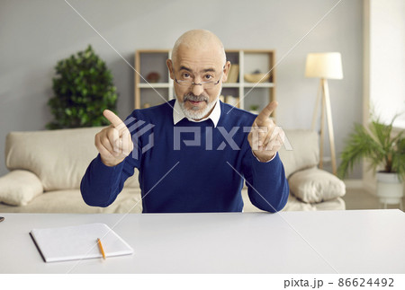 Confident senior businessman looking at camera has business talk with clients or partners online. Mature man sitting at table in front of webcam in his home office. Online services. View webcam. Confident senior businessman looking at camera has business talk with clients or partners online. Mature man sitting at table in front of webcam in his home office. Online services. View webcam. 86624492