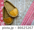 pair of handmade straw ethnic slippers on the background of linen ornamental traditional Slavic fabric with a pattern of birds and symbols 86625267