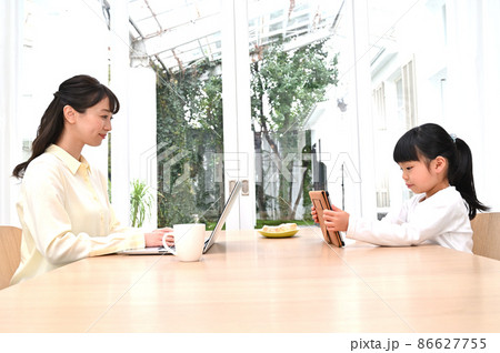 向かい合って仕事をする母親と学習する女の子 向かい合って仕事をする母親と学習する女の子 86627755