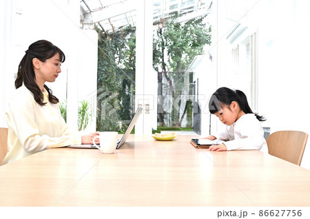 向かい合って仕事をする母親と学習する女の子 向かい合って仕事をする母親と学習する女の子 86627756