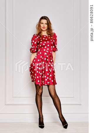 Portrait of young woman in dotted satin dress and polka dot tights Portrait of young woman in dotted satin dress and polka dot tights 86628091