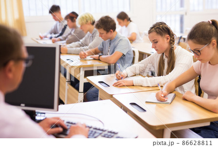 Teenage students studying in classroom with teacher Teenage students studying in classroom with teacher 86628811
