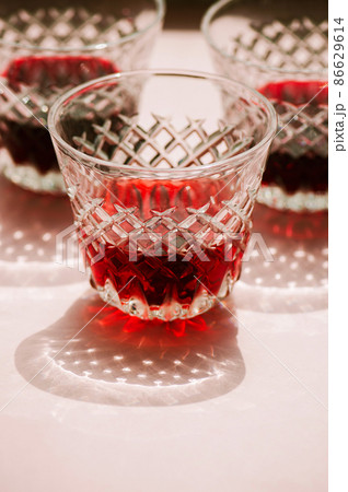 Red wine in a transparent glass with abstract shadows on pink background. 86629614