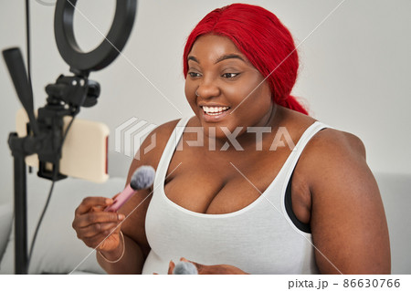 Multiracial woman preparing applying blush on her chicks while broadcasting make up tutorial 86630766