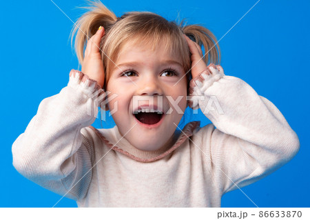 Beautiful little girl with hands on head being delighted and shocked over blue background. Beautiful little girl with hands on head being delighted and shocked over blue background. 86633870