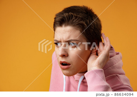 Young girl doing listen gesture with hand on ear over yellow background 86634094