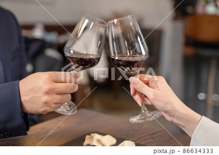 飲食店にてワインで乾杯をする男女の手元 飲食店にてワインで乾杯をする男女の手元 86634333