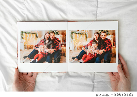 a hands with a book with photos of big family on a white background. 86635235