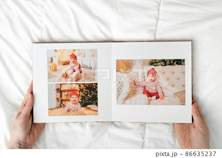a hands with a book with photos of little child on a white background. 86635237