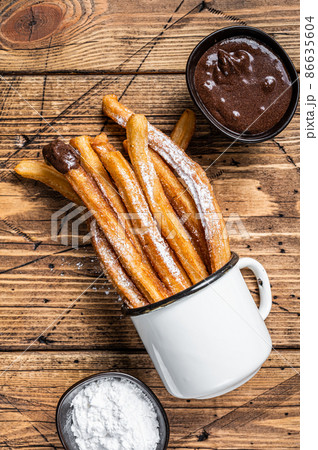 Churros with sugar and chocolate sauce. wooden background. Top view 86635604