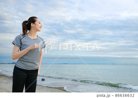 海沿いを走るスポーツウェアの女性 86636632