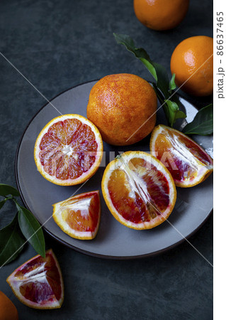 Bloody oranges on dark background, whole and slice with leaves. Fresh citrus fruits in plate. 86637465