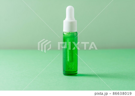 Facial liquid cosmetic product with bubbles on green background. Front view, copy space Facial liquid cosmetic product with bubbles on green background. Front view, copy space 86638019