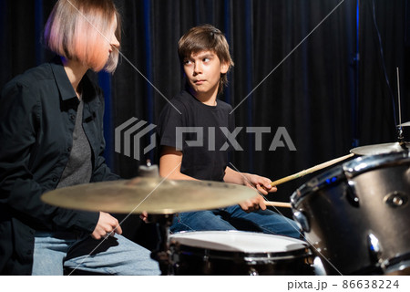 Young woman teaching boy to play drums. 86638224