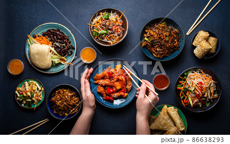 Set of Chinese dishes on table, female hands holding chopsticks 86638293