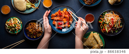 Set of Chinese dishes on table, female hands holding chopsticks Set of Chinese dishes on table, female hands holding chopsticks 86638346