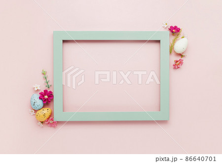 Easter holiday pink mockup background. Top view from above to different colorful Easter eggs, flowers, picture frame border. Card with copy space to place text. Minimal flat lay. High quality photo 86640701
