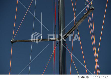 Close up view of the mast of huge sailboat at clear weather, blue sky on a background, ropes by red color 86642757