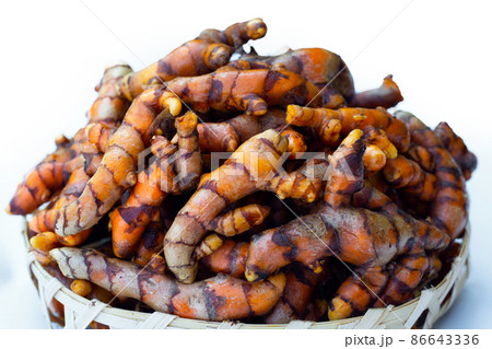 Turmeric roots on wooden spoon on white background. Turmeric roots on wooden spoon on white background. 86643336