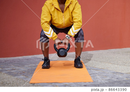 It only works when it hurts. Hard days makes champions. Cropped shot of a woman on a gym mat using a kettlebell against an urban background. It only works when it hurts. Hard days makes champions. Cropped shot of a woman on a gym mat using a kettlebell against an urban background. 86643390