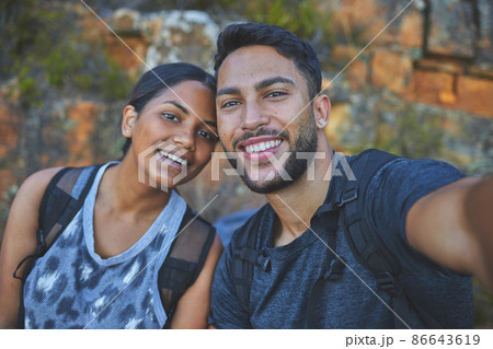 I want to remember this forever. Shot of a young couple taking photos while out on a hike in a mountain range outside. 86643619