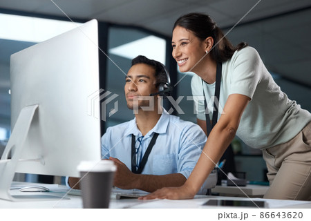 Passing on sage customer service advice. Shot of a young man and woman using a computer while working in a call centre. Passing on sage customer service advice. Shot of a young man and woman using a computer while working in a call centre. 86643620