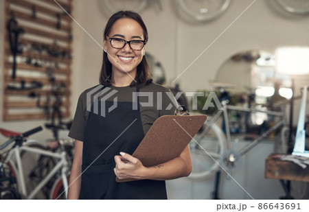 Just finished up with a stocktake. Shot of an attractive young woman standing alone in her bicycle shop and holding a clipboard. Just finished up with a stocktake. Shot of an attractive young woman standing alone in her bicycle shop and holding a clipboard. 86643691