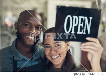 Were finally open. Shot of a young couple standing together and turning the sign on the door to their bicycle shop. 86643697