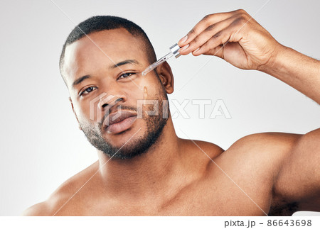 Use serum for a smoother, brighter complexion. Studio portrait of a handsome young man applying serum to his face with a dropper against a white background. Use serum for a smoother, brighter complexion. Studio portrait of a handsome young man applying serum to his face with a dropper against a white background. 86643698