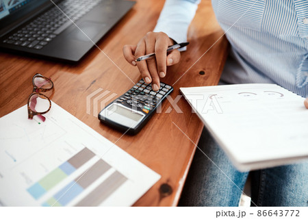 Business is a numbers game. Cropped shot of a businesswoman using a calculator while going over financial paperwork at her desk. 86643772
