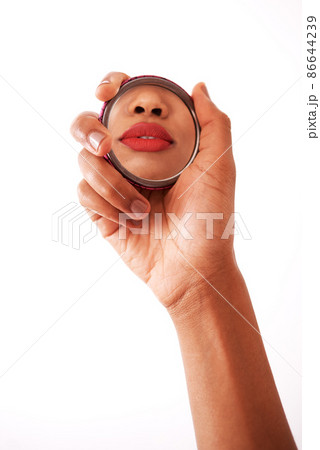 My lips are on point. Studio shot of an unrecognizable woman holding a pocket size mirror against a white background. 86644239