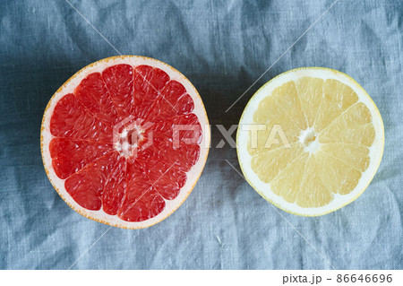 Two halves of red and white grapefruit, bright circles on a dark gray linen background Two halves of red and white grapefruit, bright circles on a dark gray linen background 86646696