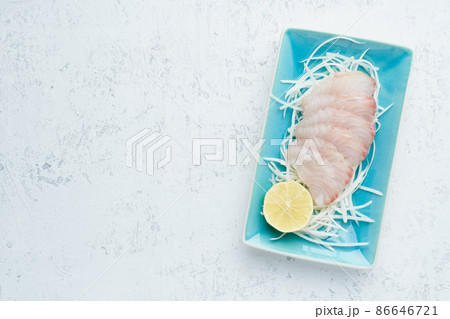 Sashimi from slices of raw white fish fillet on a blue plate on a white background. Copy space Sashimi from slices of raw white fish fillet on a blue plate on a white background. Copy space 86646721