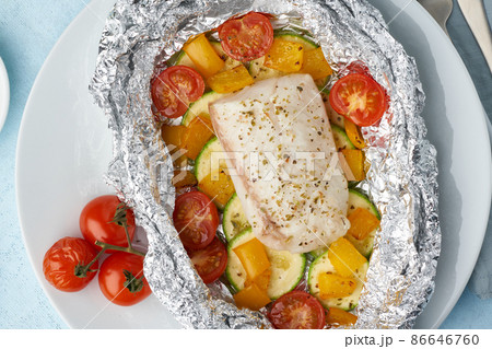 Foil pack dinner with white fish. Oven baked fillet of cod, pike perch with vegetables 86646760
