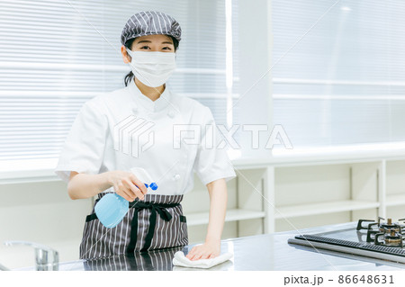 キッチンを除菌清掃するコックコートの女性 86648631