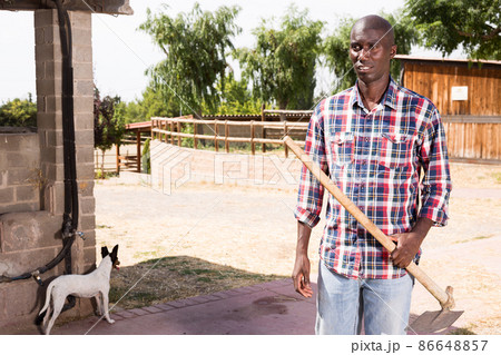 Young african american man farmer with rake standing at farm Young african american man farmer with rake standing at farm 86648857
