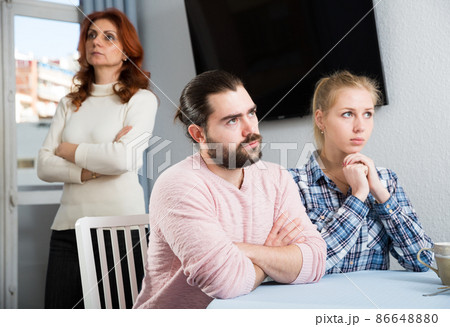 Upset mature woman talking with sad daughter and her boyfriend at home 86648880