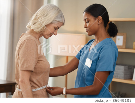 Whats better than dieting A diet thats doctor approved. Shot of a doctor using a measuring tape on a senior womans stomach during a consultation at home. 86649105