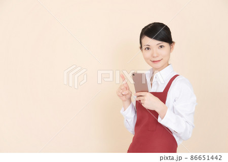 スマートフォンを操作するエプロンの女性 86651442
