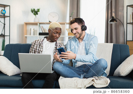 Two gays using laptop and smartphone at home 86658360