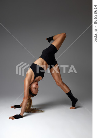 Animal instinct fitness female instructor showing his incredible flexibility with an animal flow move in studio against a gray background 86658614
