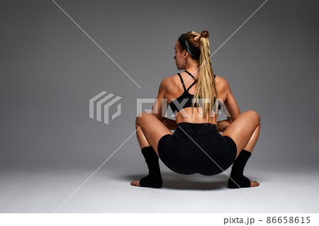 Animal instinct fitness female instructor showing his incredible flexibility with an animal flow move in studio against a gray background 86658615