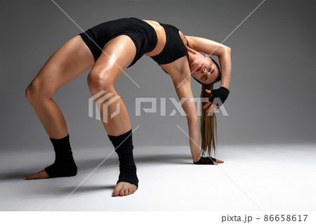 Animal instinct fitness female instructor showing his incredible flexibility with an animal flow move in studio against a gray background 86658617