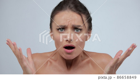 Close-up portrait of young shocked, surprised woman standing isolated over gray background while looking camera. Wow face expression. 86658849