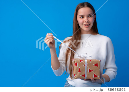 Portrait of a smiling young teen girl holding present box Portrait of a smiling young teen girl holding present box 86658891