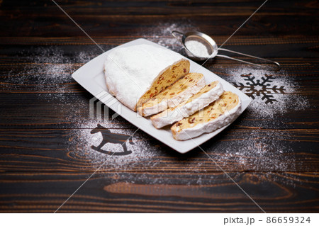Sliced Traditional Christmas stollen cake with marzipan and dried fruit on wooden background Sliced Traditional Christmas stollen cake with marzipan and dried fruit on wooden background 86659324