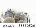 Warm winter women's boots of gray color with fur on a background of snow. 86660520