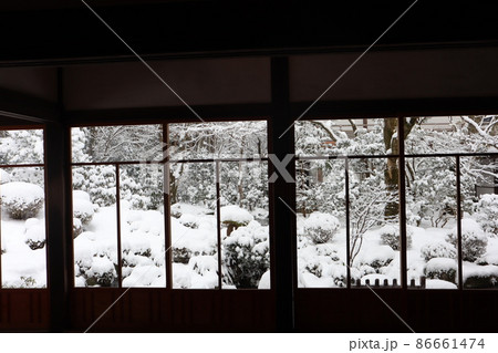 日本家屋の室内の大きな格子窓から見た雪景色の庭の風景の写真素材
